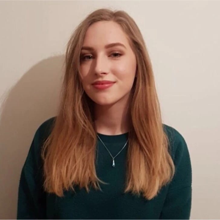 Redheaded girl wearing a green sweater and smiling at the camera