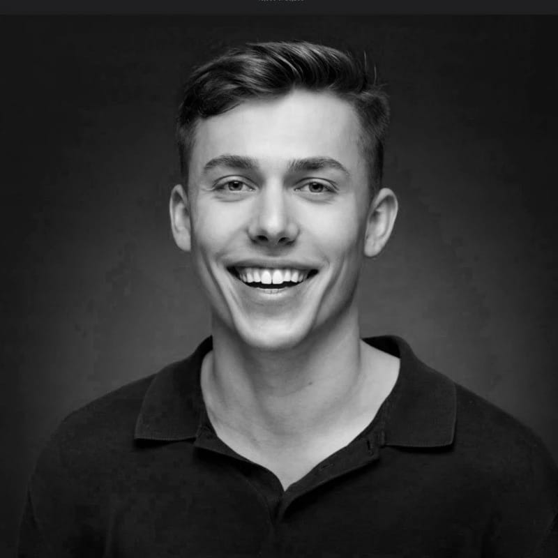 Smiling young man with short hair in a black polo shirt, black and white photo.