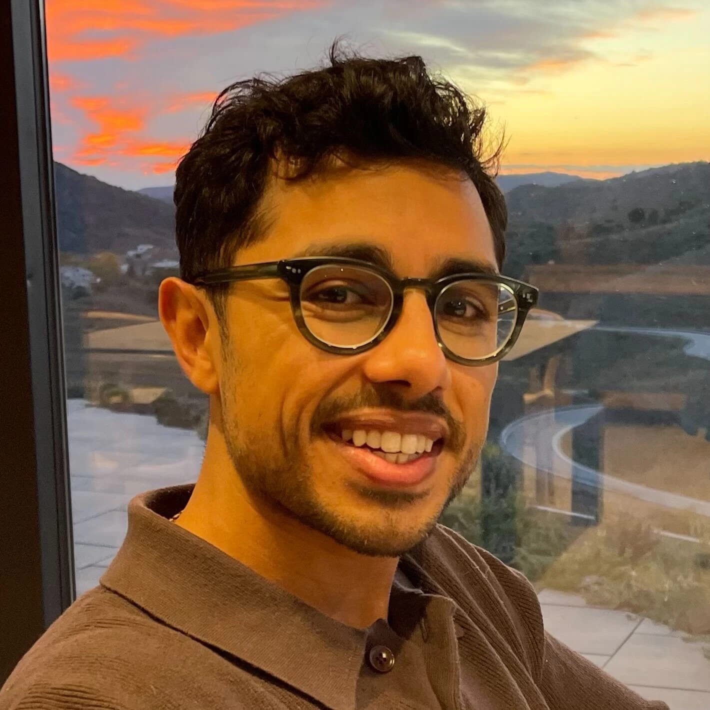 man smiling in front of a sunset