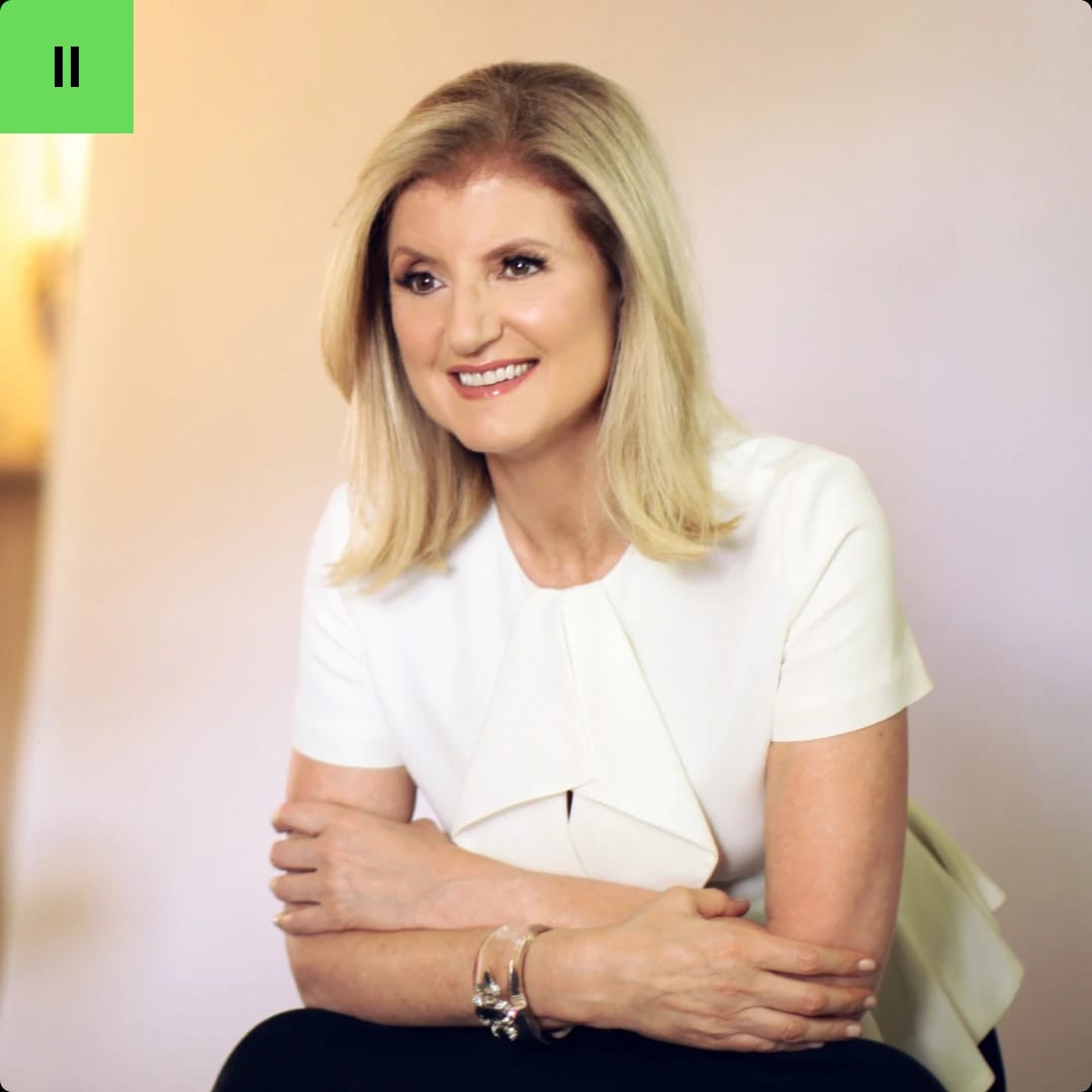 A woman with blonde hair smiling, wearing a white top, sitting with her arms crossed.