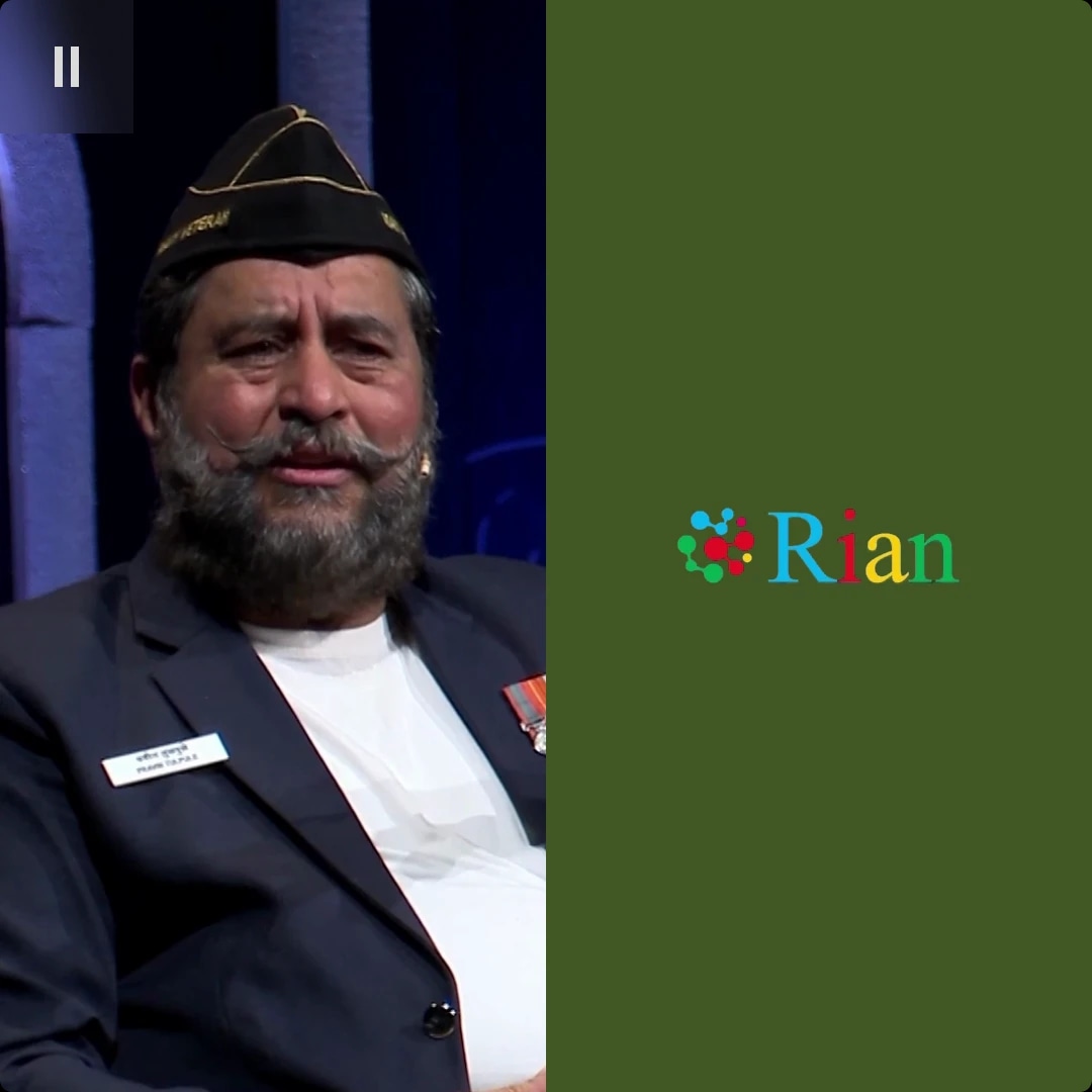 A man with a beard and mustache, wearing a military-style cap and a suit with medals, sitting indoors.