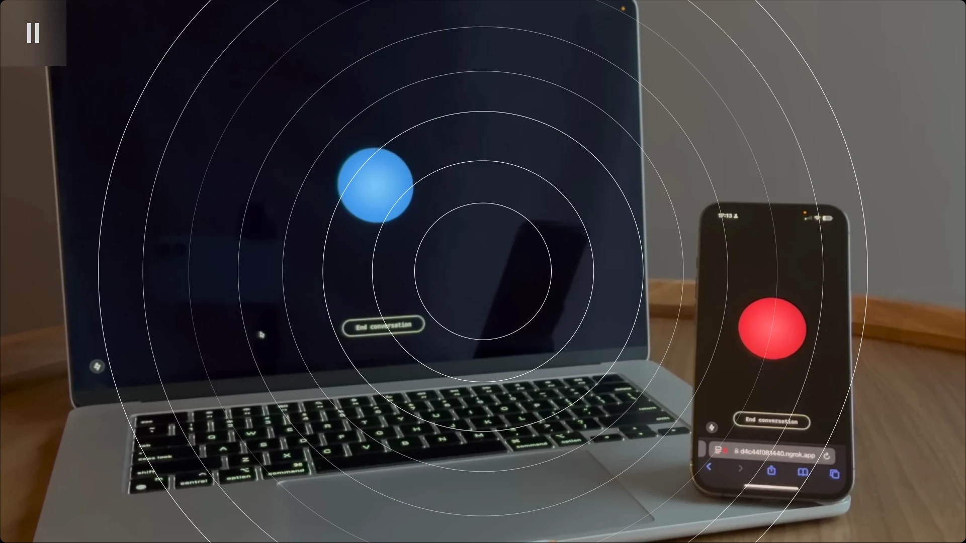 A laptop and a smartphone on a wooden surface, both displaying incoming video call screens with a red and blue circle, respectively.