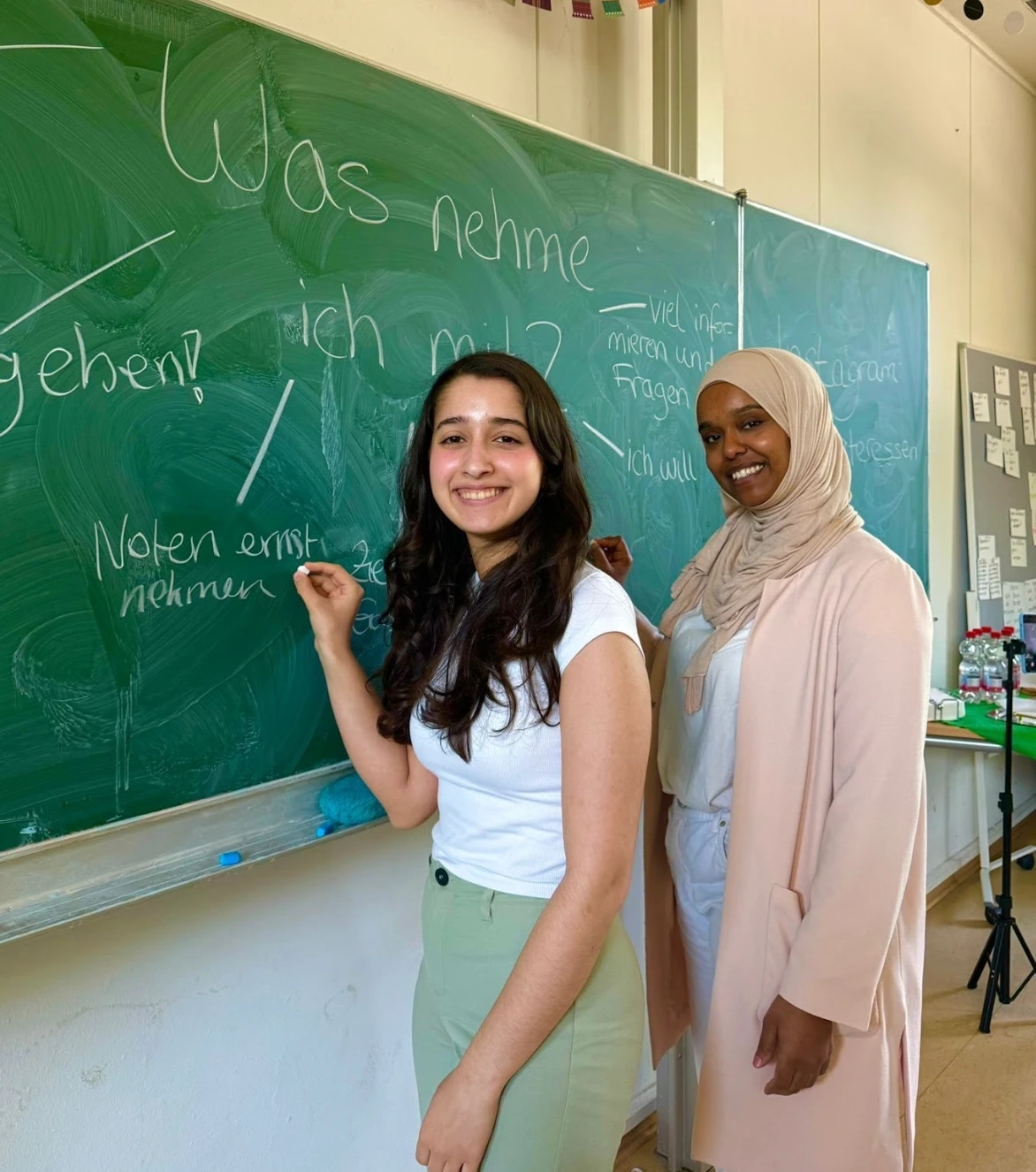 Two young women stand at a chalkboard