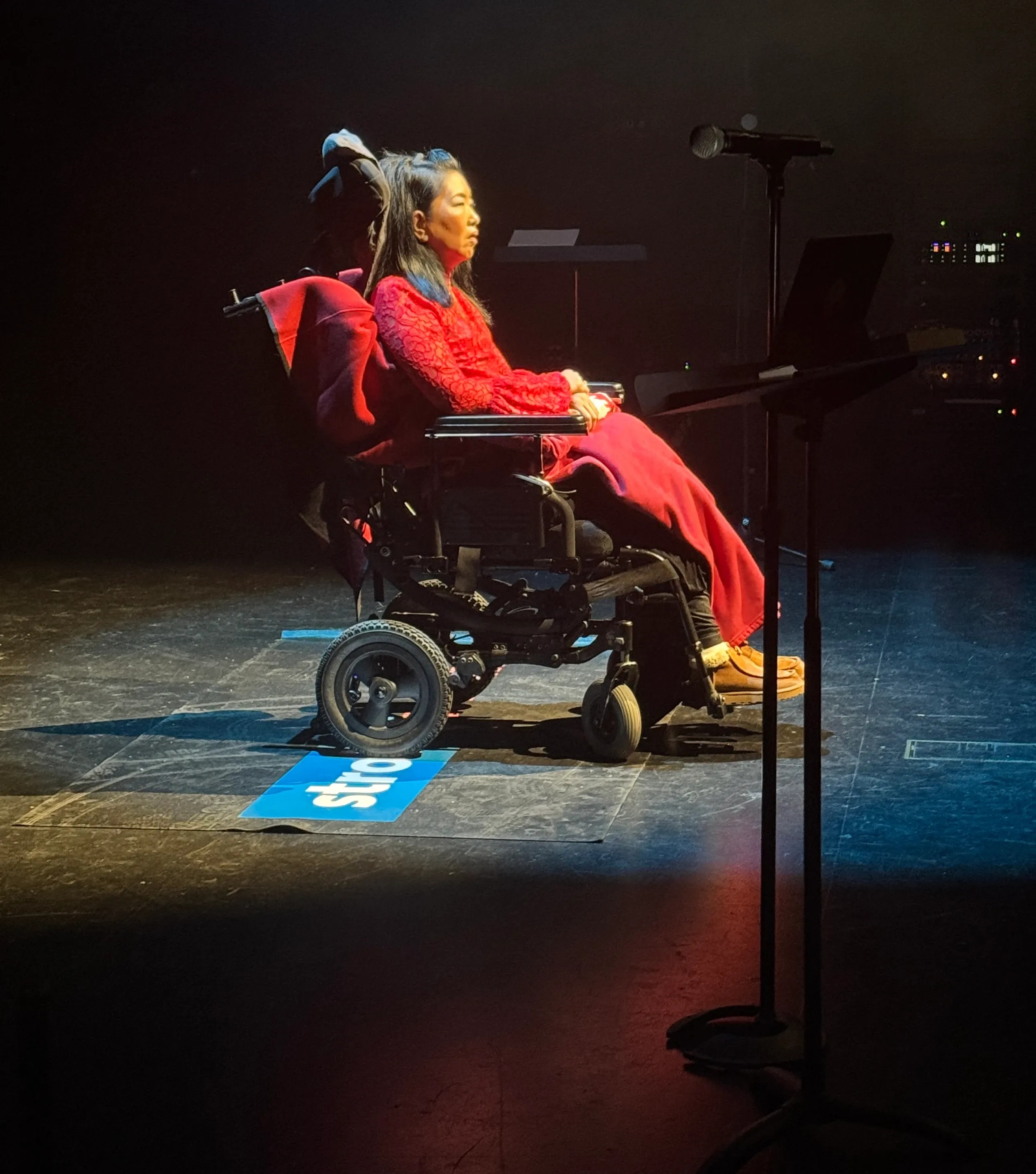 Woman in a red dress sitting on stage in a wheelchair