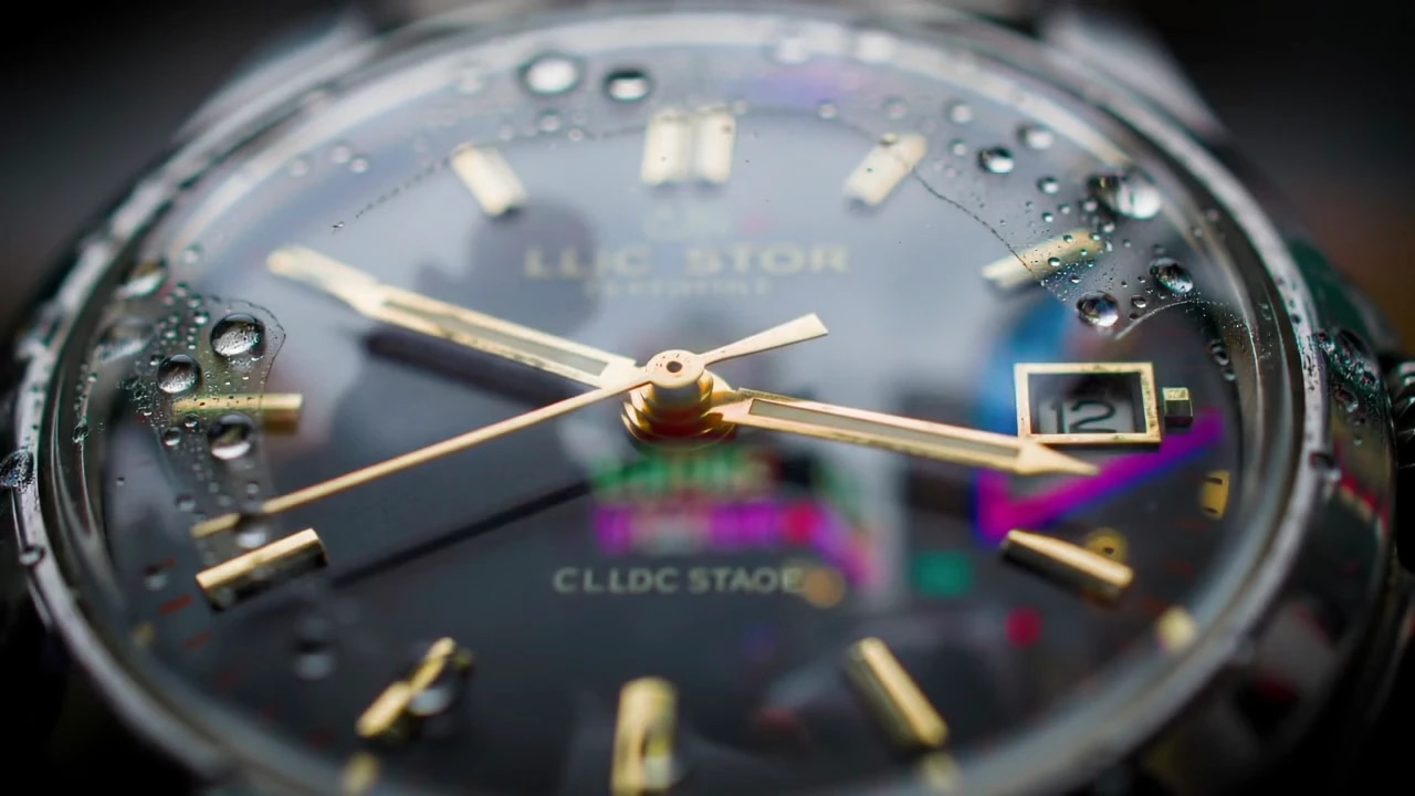 Close-up of a wristwatch with water droplets on the glass, showing the time and date.