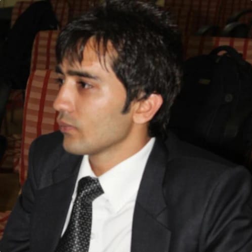 A man in a suit and tie sitting in a conference room.