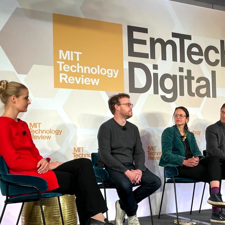 Four people sitting on chairs on a stage during a panel discussion at MIT Technology Review EmTech Digital event.