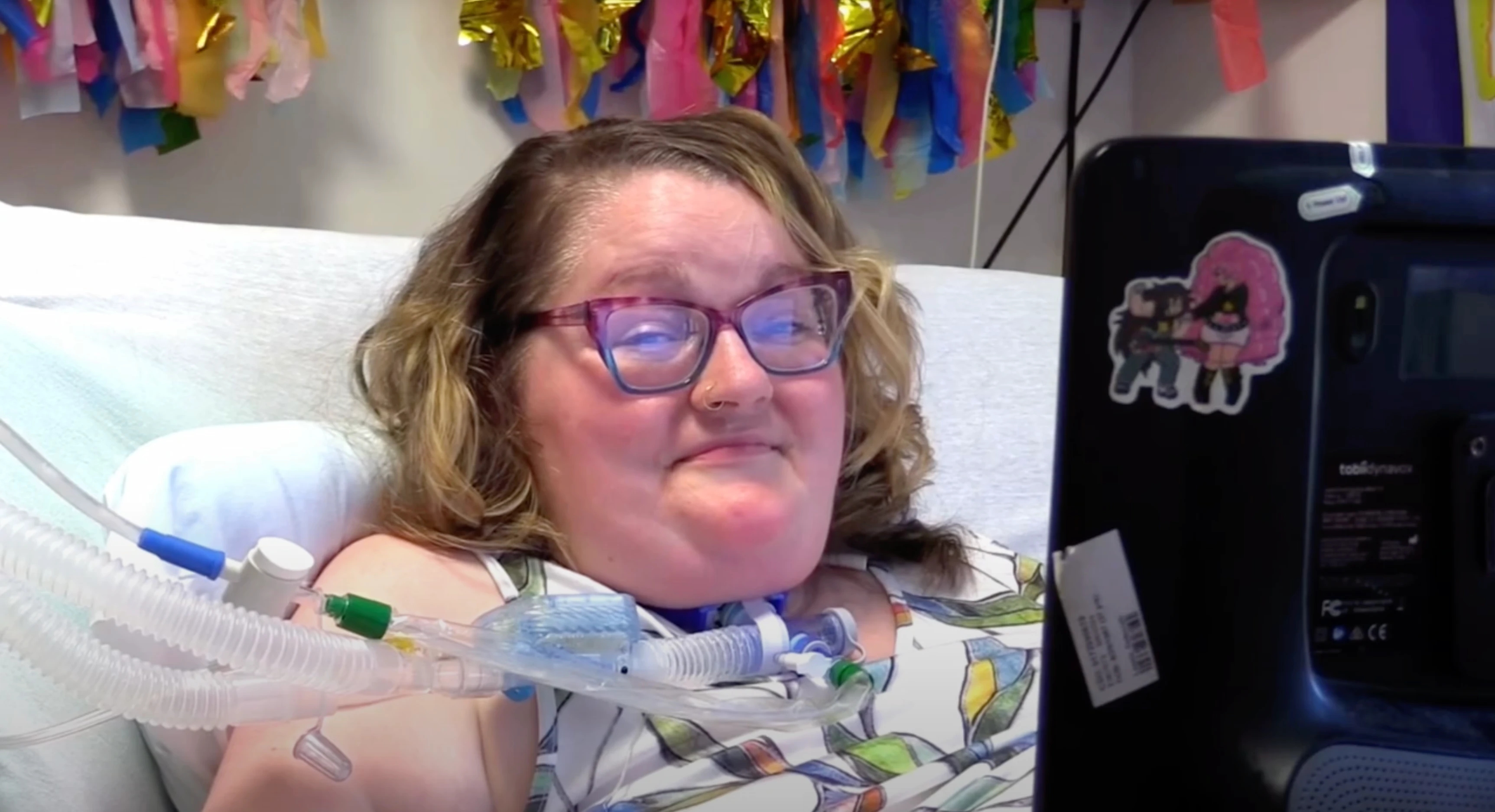 Woman with ALS lying in a hospital bed, smiling