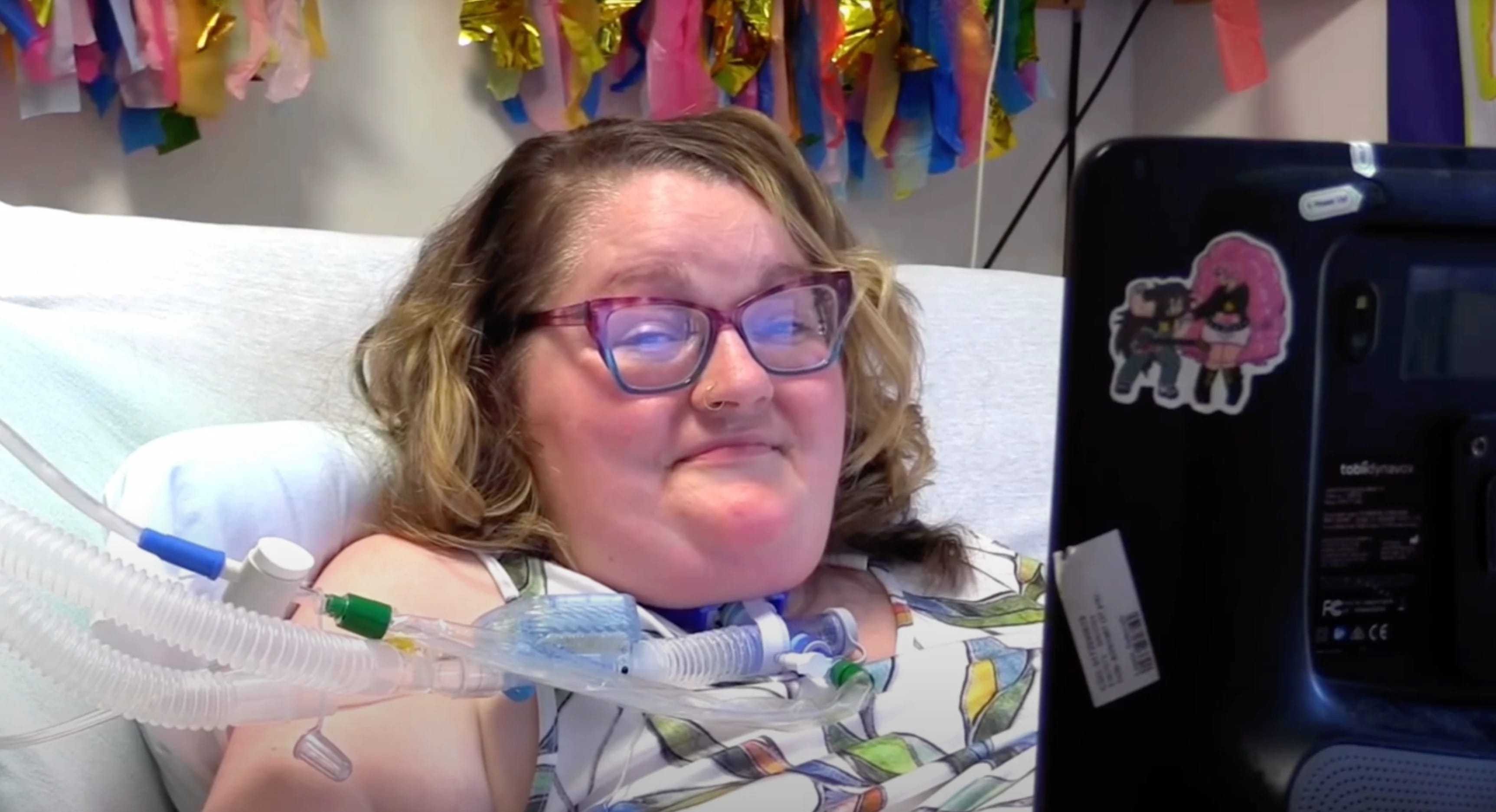 Woman with ALS lying in a hospital bed, smiling